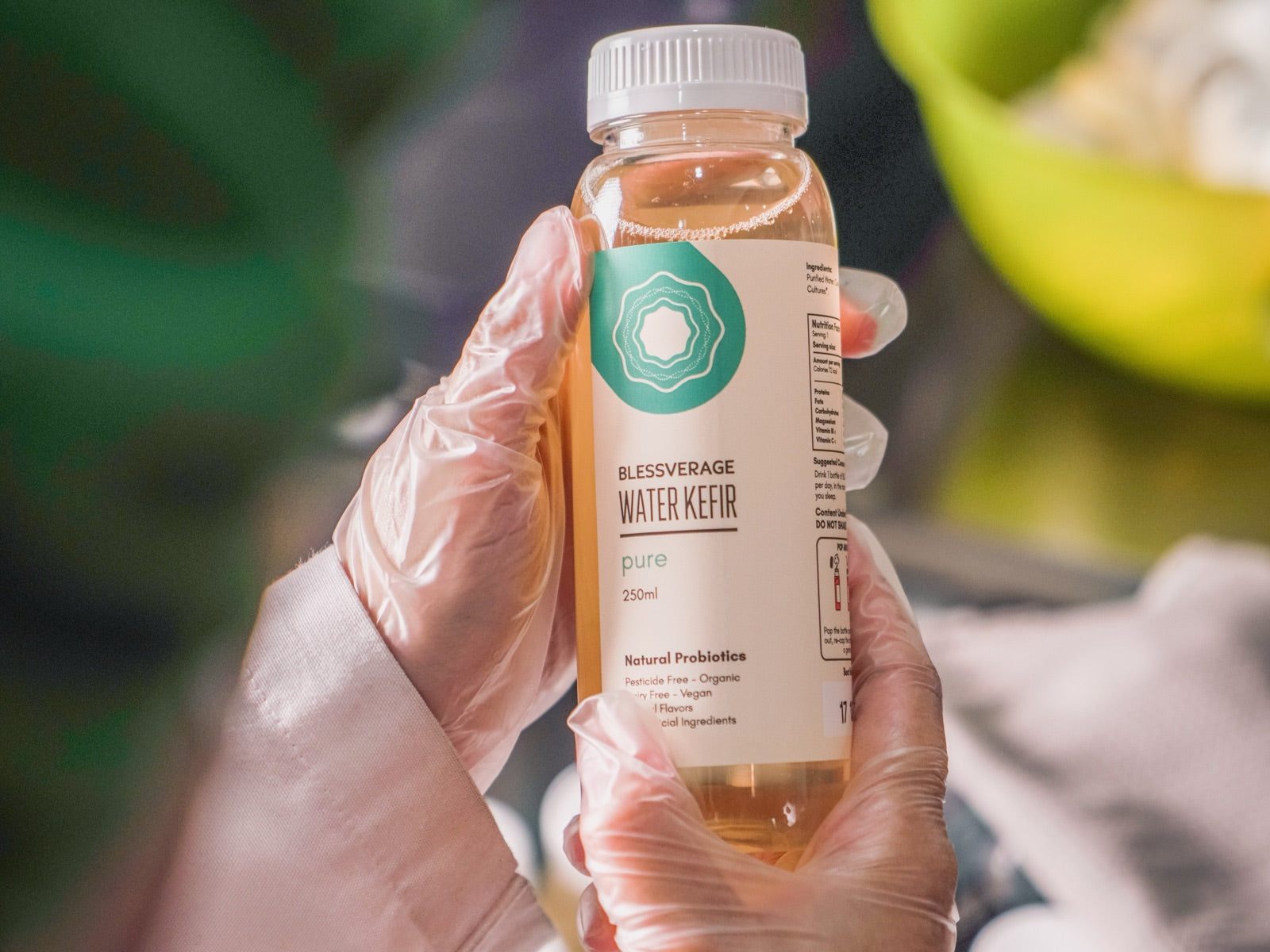 A bottle of mangosteen water kefir on a studio backdrop
